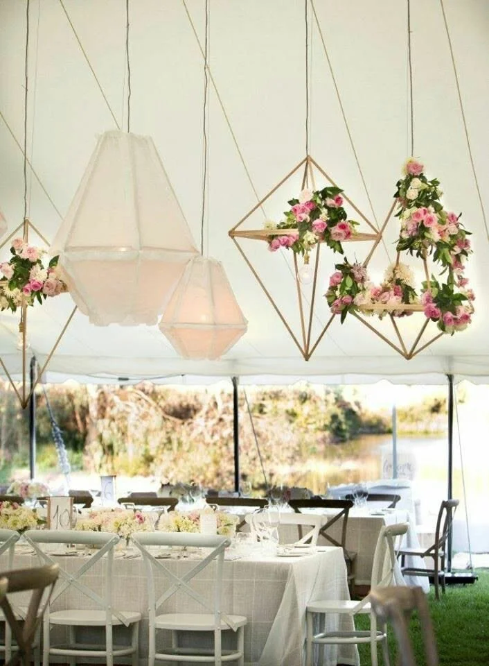 Geometric hanging frames with pink florals suspended in a marquee
