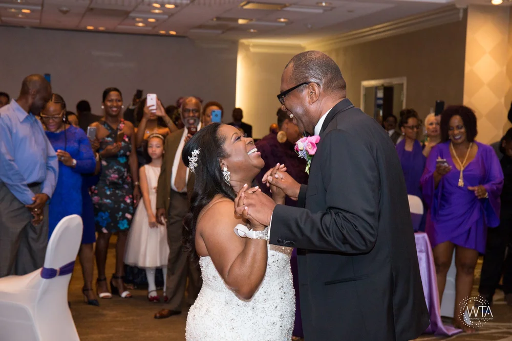 Bride in a strapless gown laughing with an older guest at an indoor reception