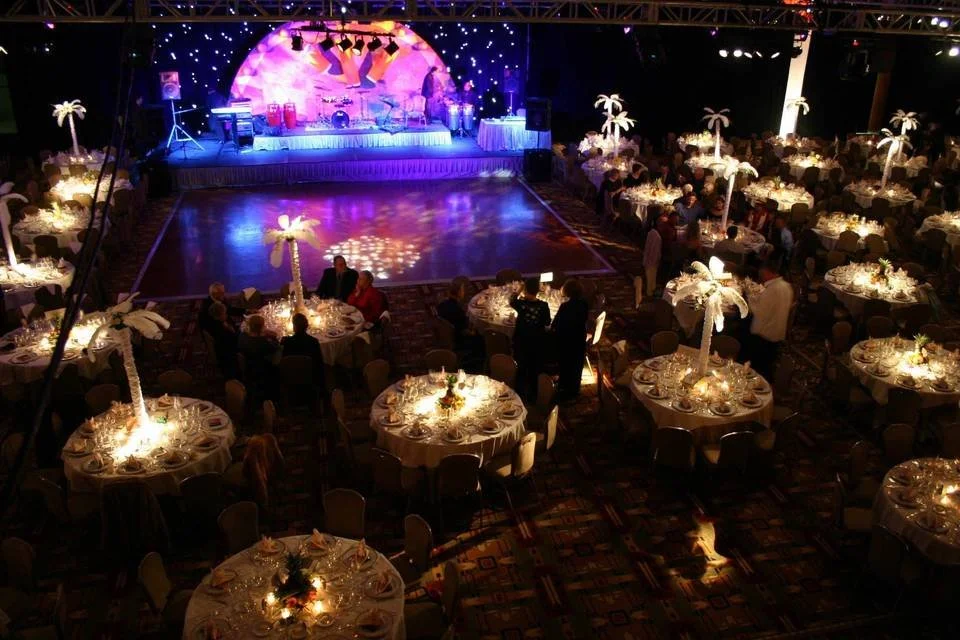 Large reception hall lit in magenta and blue with a mirrored dance floor