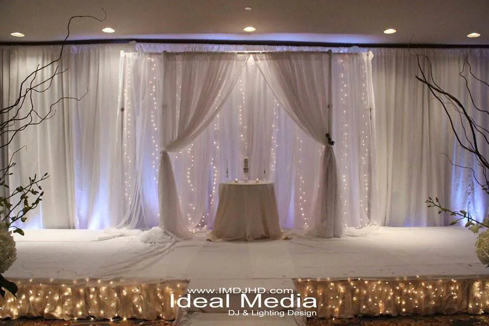 Ceremony backdrop of white draping with fairy lights behind a signing table