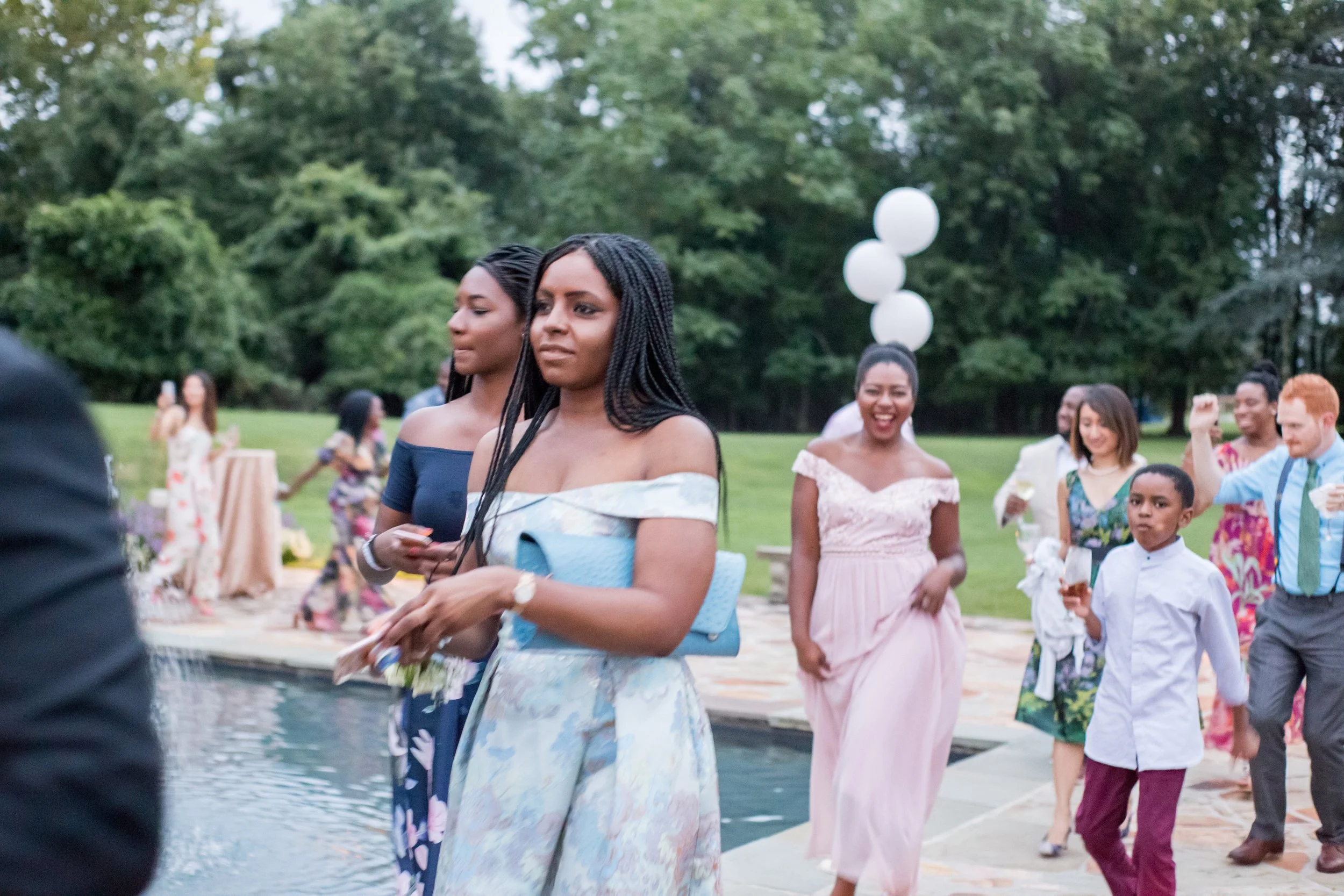 Guests in pastel dresses at an outdoor poolside celebration
