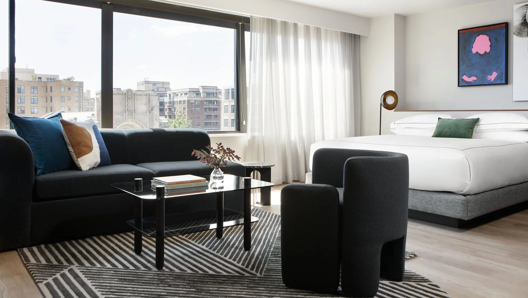 Hotel guest room seating area with black armchairs and a city view