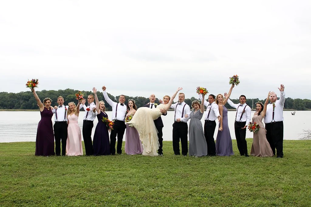 Wedding party cheering together on a lawn overlooking the water