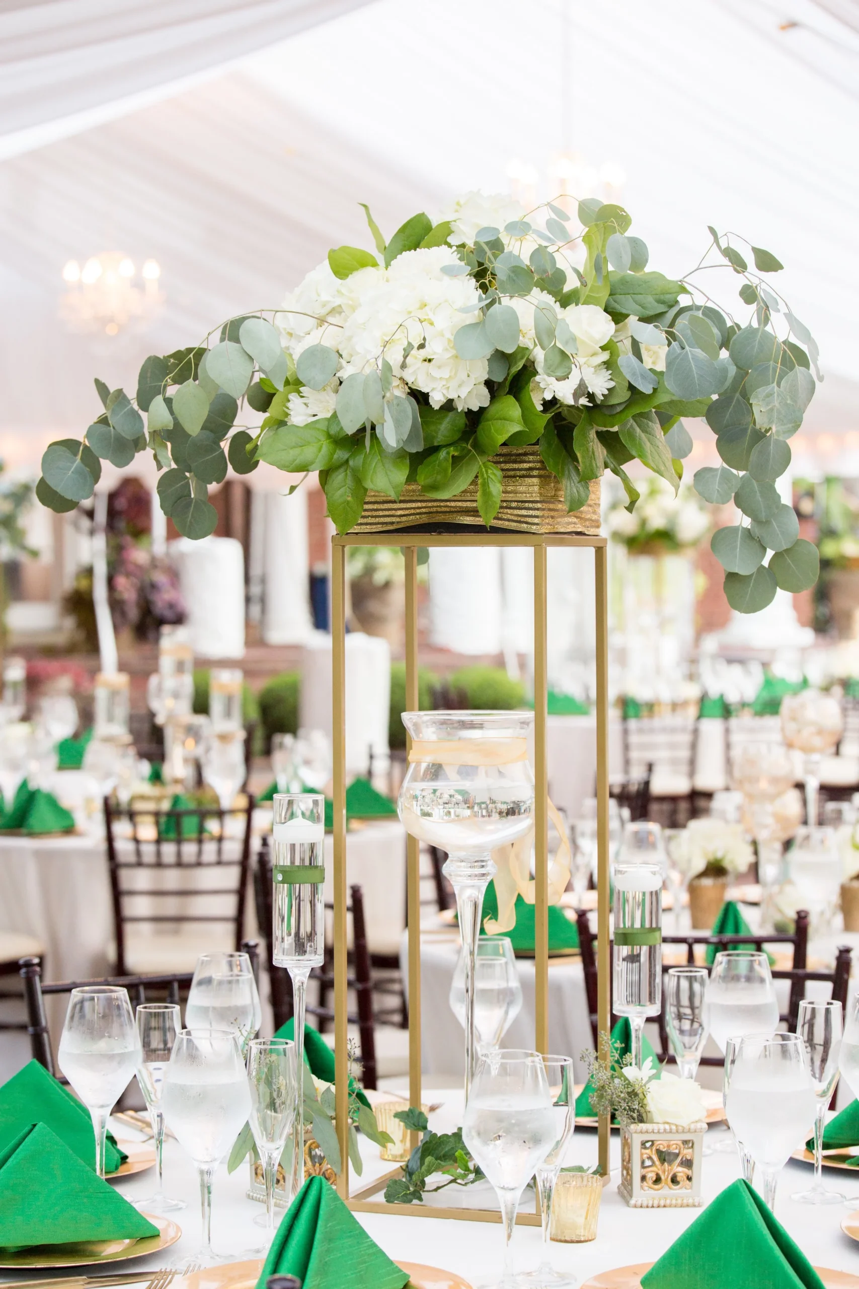 Tall gold stand centrepiece with white hydrangea and eucalyptus above the tables