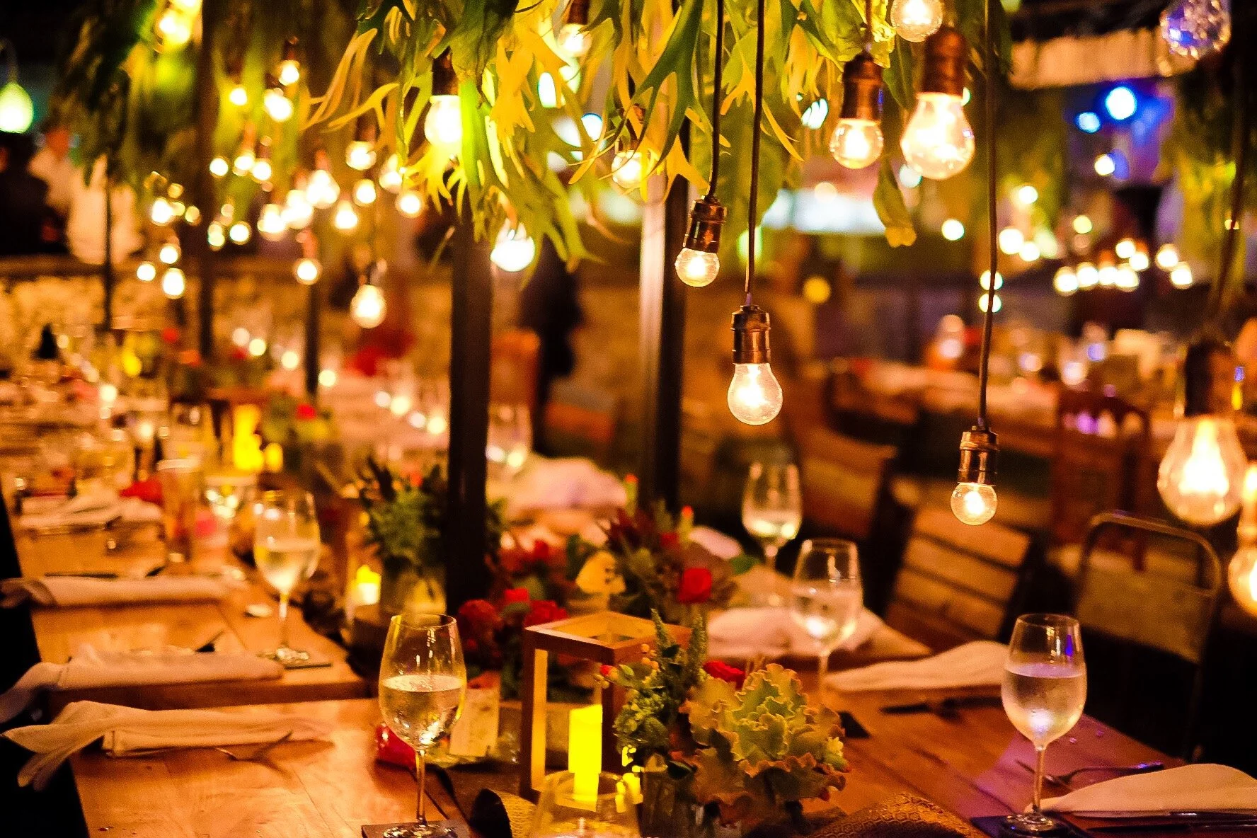 Outdoor reception tables lit by warm Edison bulb string lights overhead