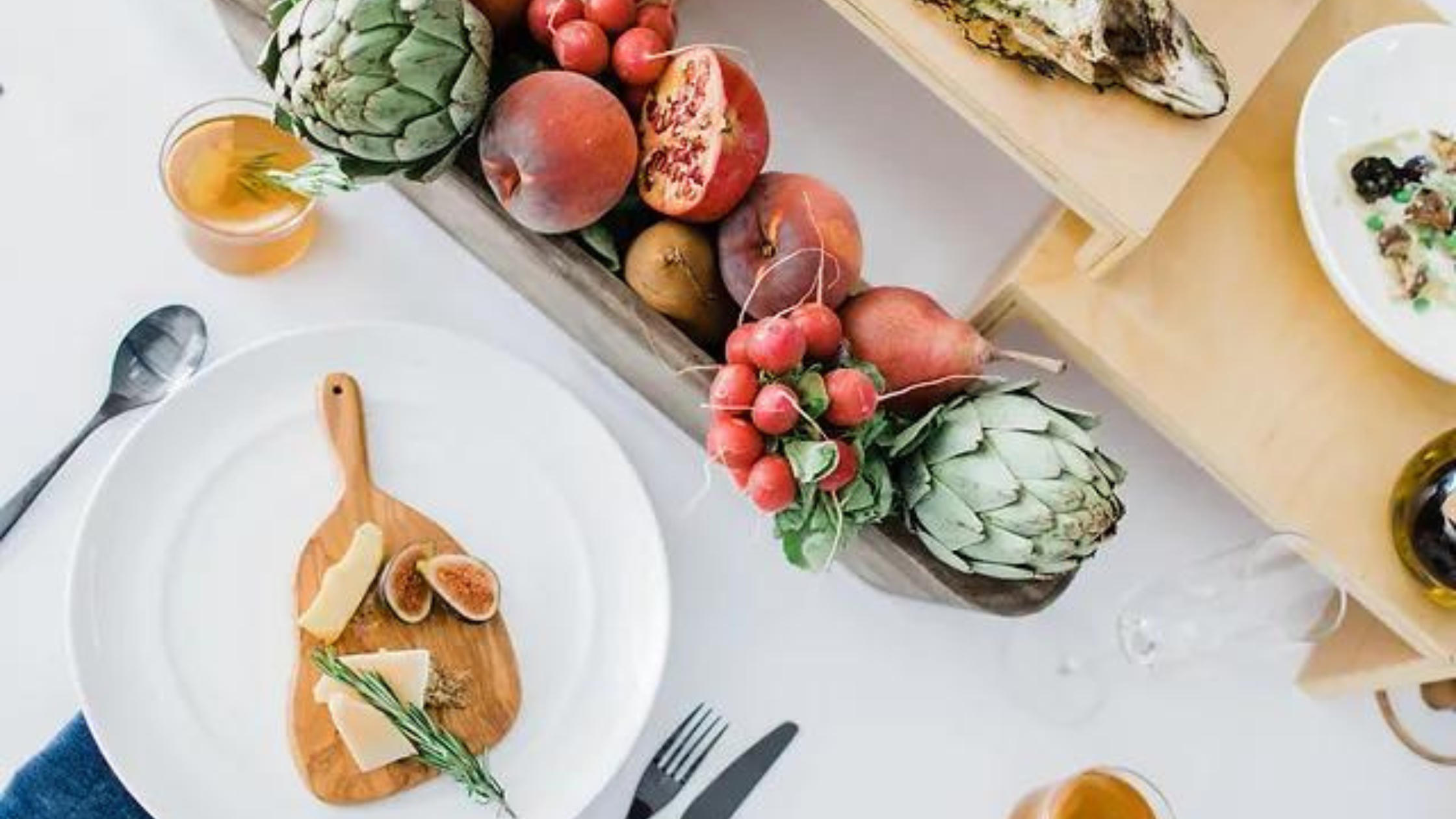 Seasonal produce and a cheese board arranged on a white table