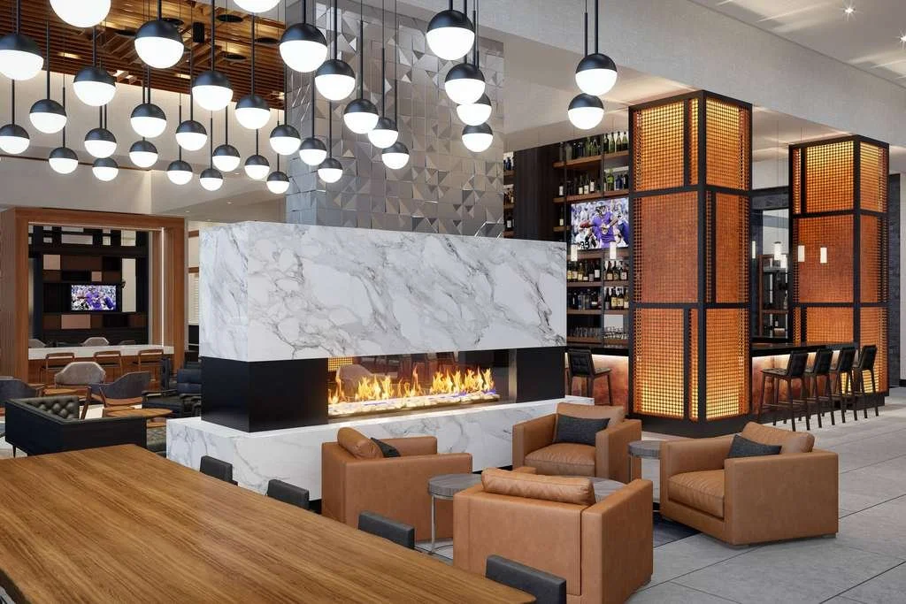 Modern hotel bar with a marble feature wall, fireplace and pendant lights