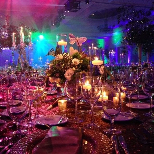 Reception table in deep jewel lighting with candles and lush centrepieces