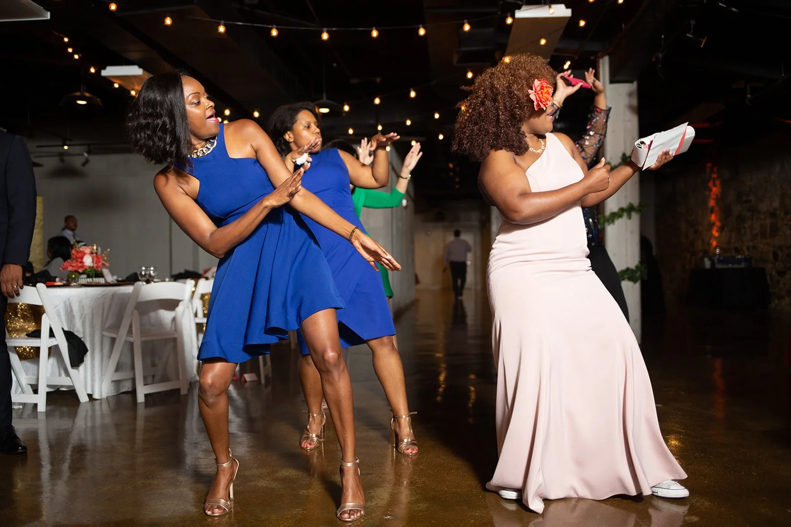 Wedding guests dancing together on the reception floor under string lights