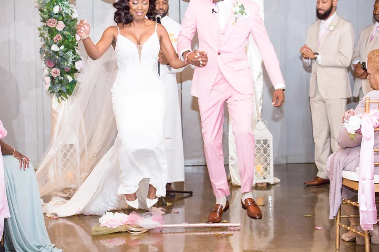Bride in a fitted white gown and groom in a blush suit walking together after the ceremony