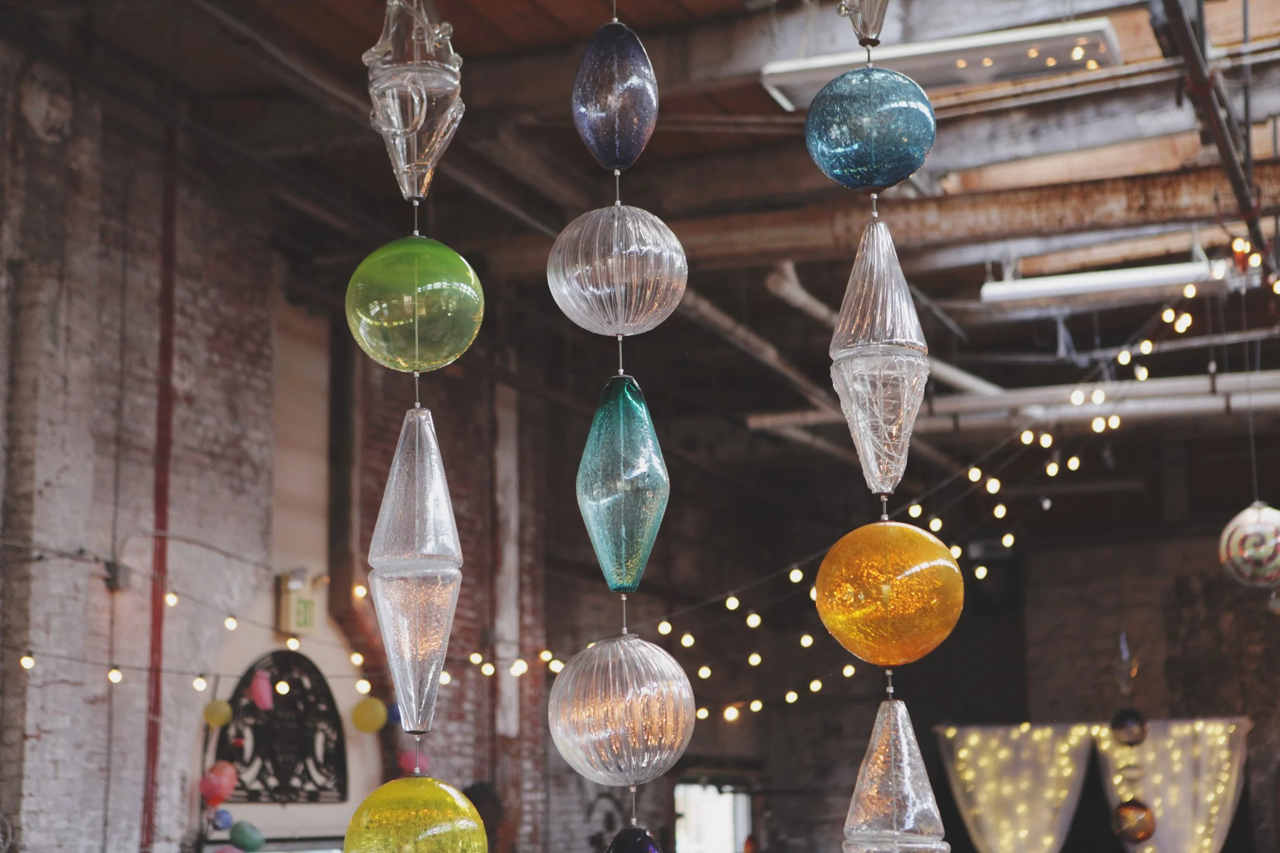 Hanging glass orb installation in jewel tones above a reception space