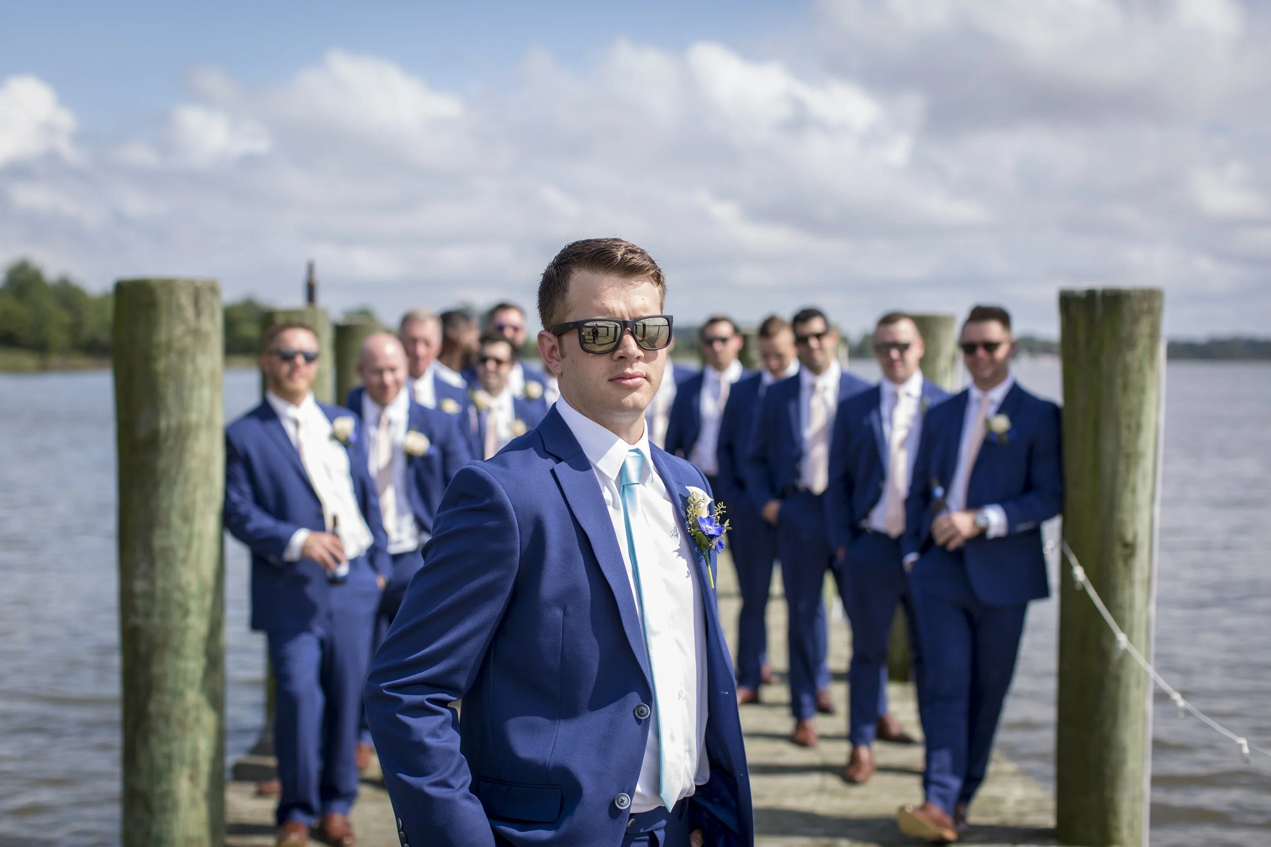 Groom with his groomsmen in navy suits on a waterfront dock