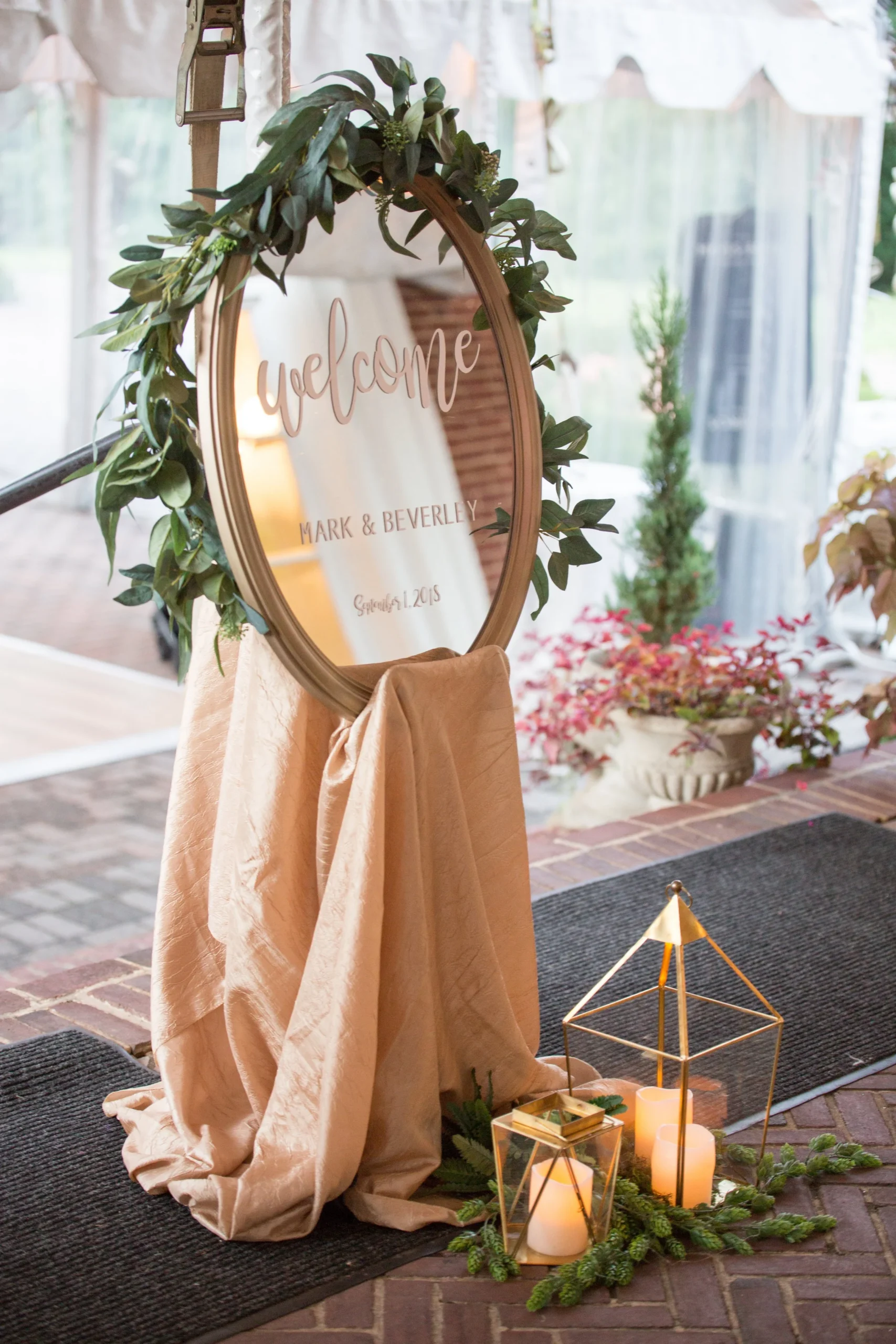 Gold framed welcome mirror sign with eucalyptus at a reception entrance