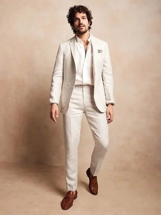 Model wearing a cream linen suit against a warm neutral backdrop