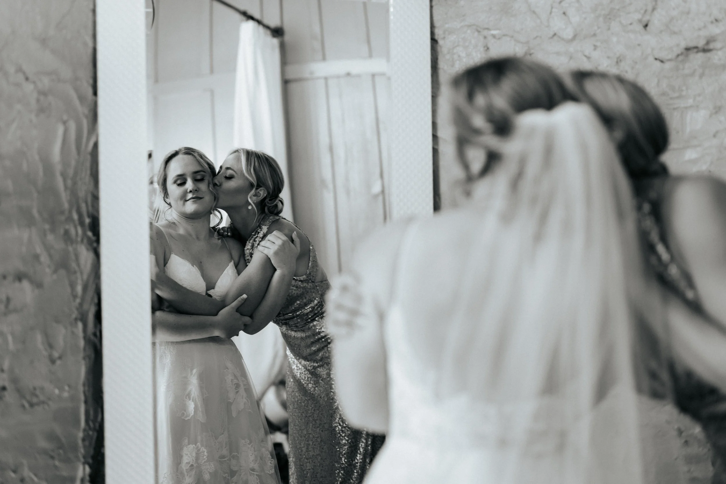Black and white photo of a bride embracing family members before the ceremony