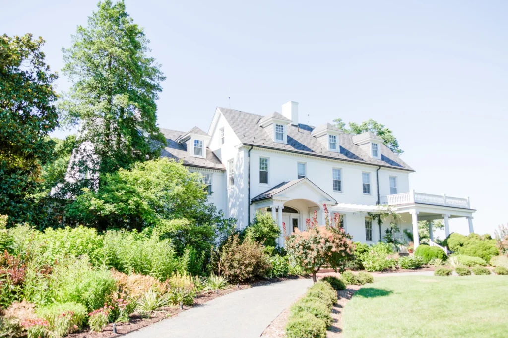 White colonial style estate house with landscaped gardens