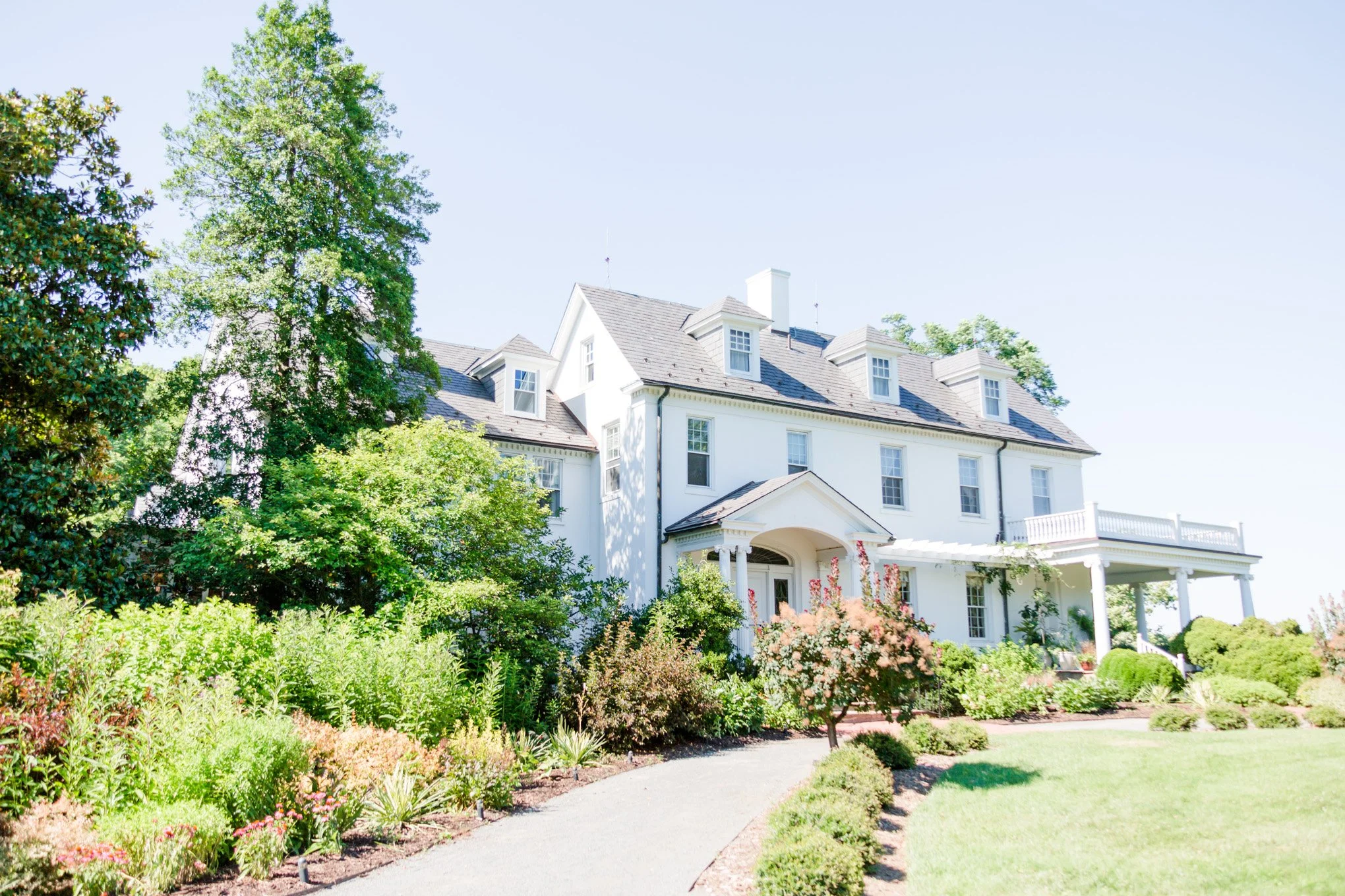 White colonial style estate house with landscaped gardens