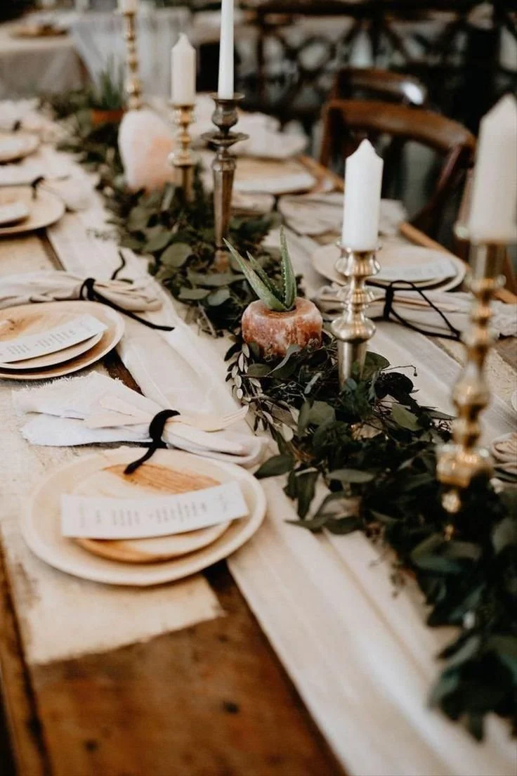 Neutral tablescape with eucalyptus runner, taper candles and menu cards