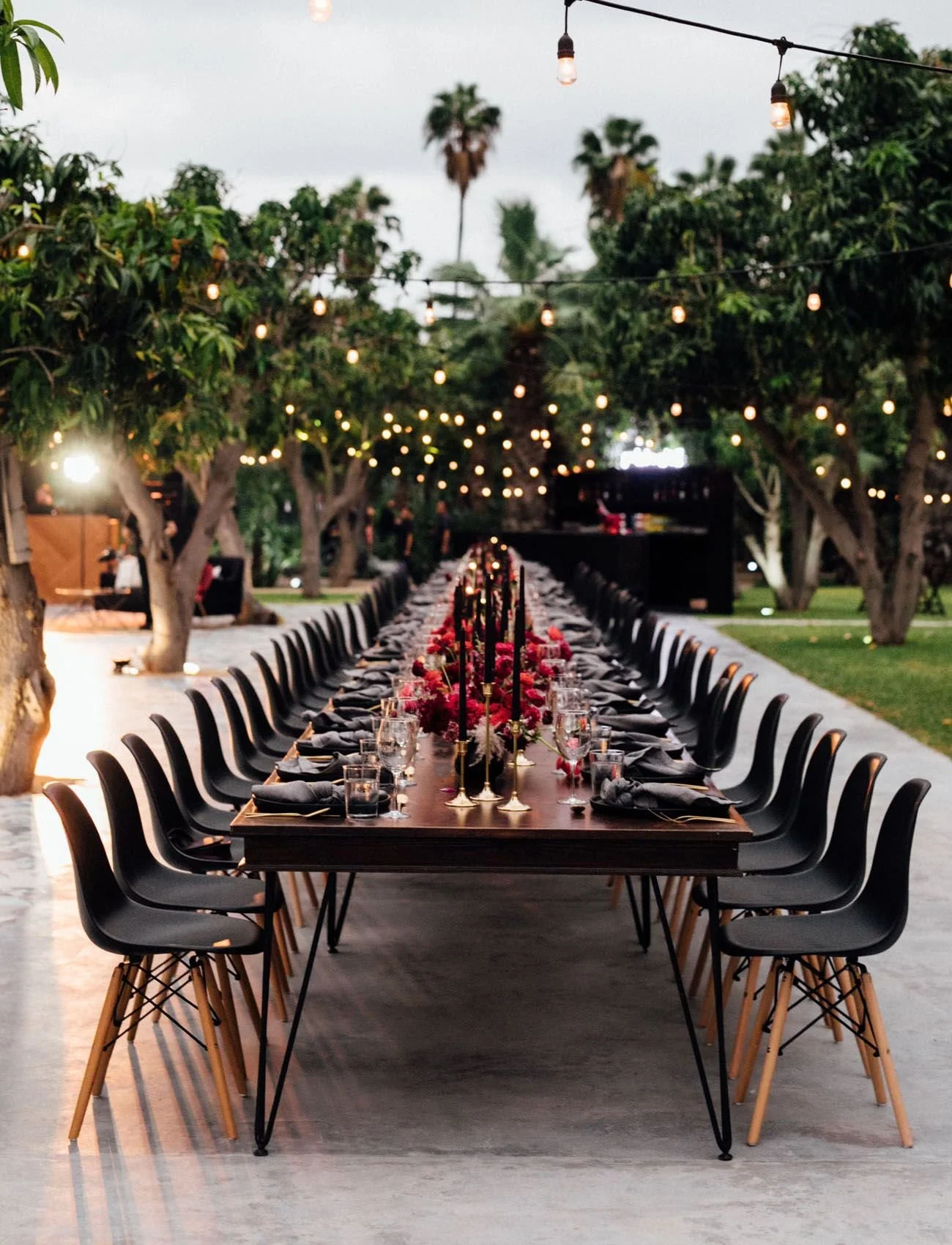 Long outdoor banquet table under string lights in a garden at night