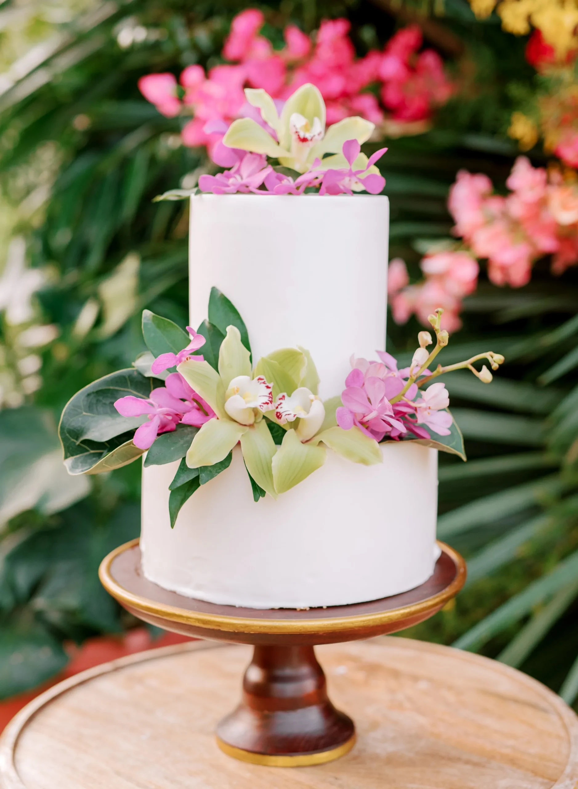 Tropical Wedding Cake with flowers on a wooden cake stand.