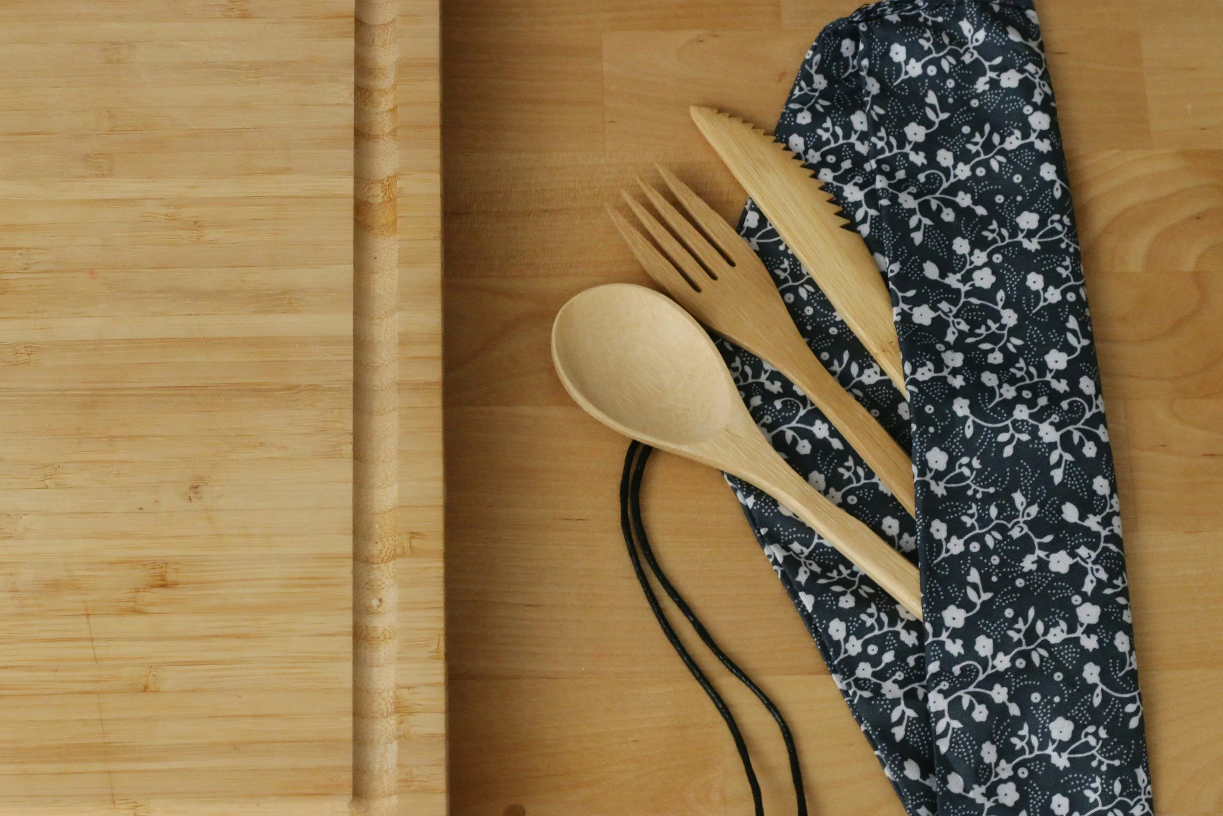 Bamboo cutlery set on a floral napkin over a wooden board