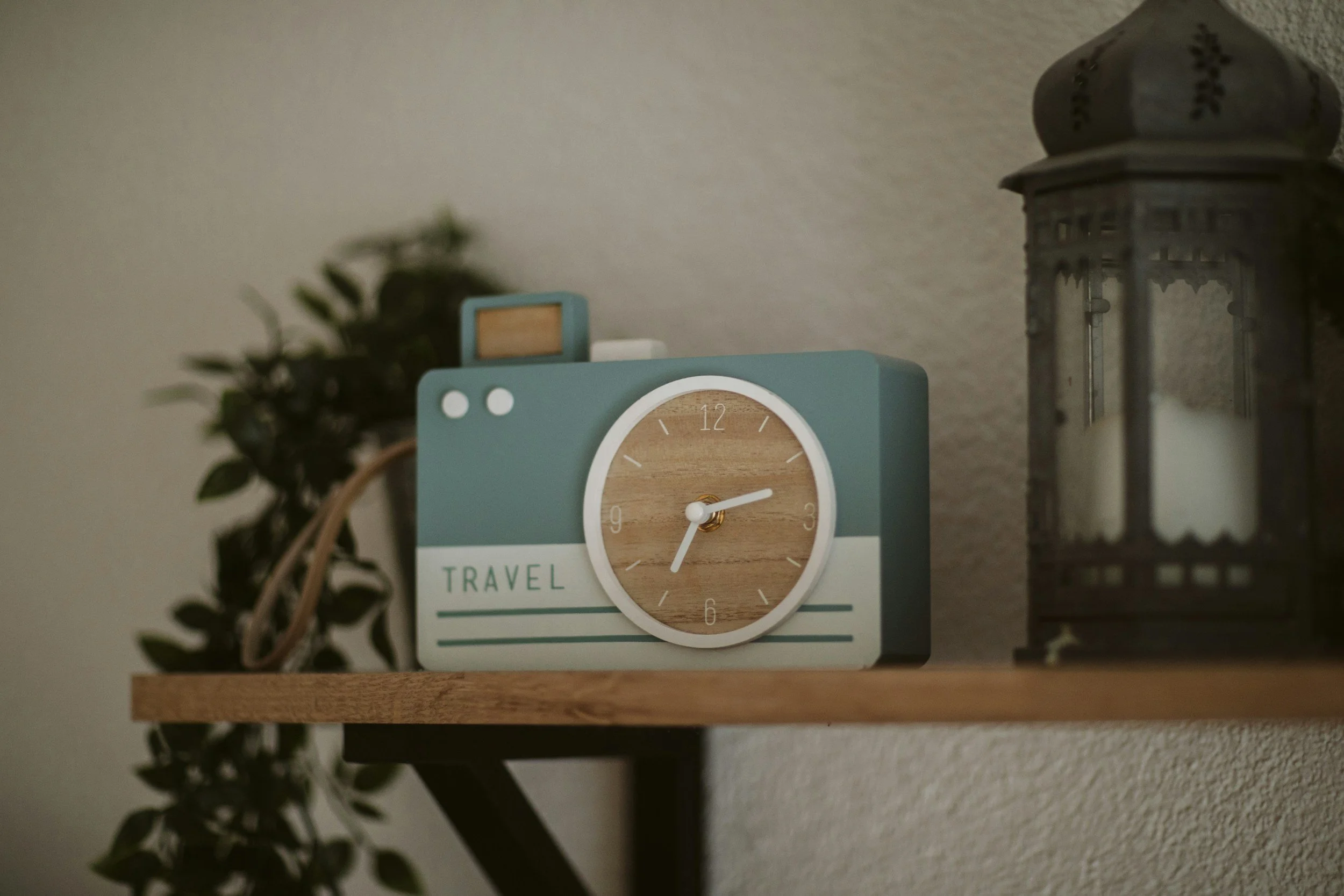 Vintage table clock on a shelf beside a lantern and greenery