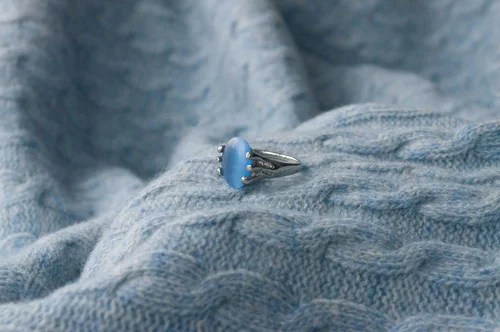 Sapphire and diamond engagement ring on a grey knit blanket