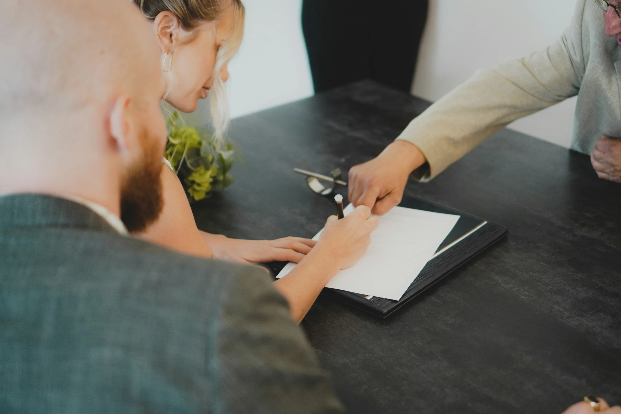 Two people signing a vendor contract across a table