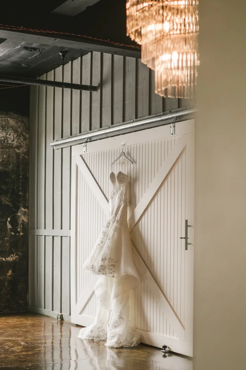 Wedding dress on a hanger against a white panelled barn door