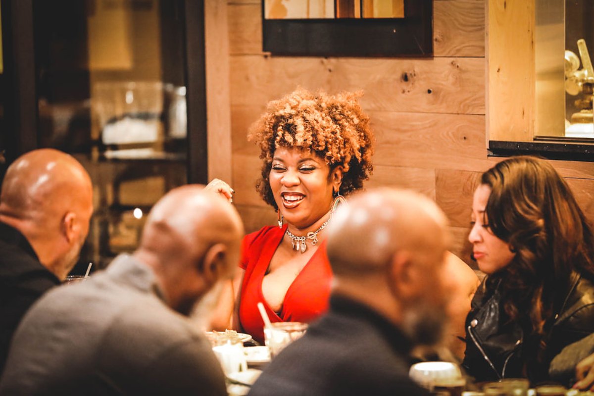 Friends laughing together at a dinner celebration in the DMV